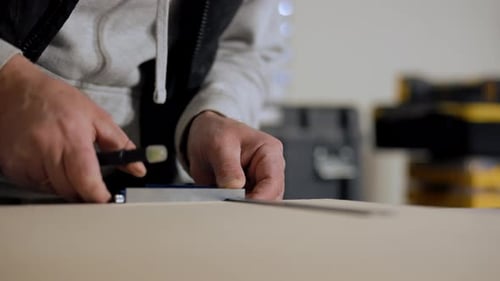 Close Up View of Carpenter Measuring and Marking Wooden Board with Ruler and Pencil During