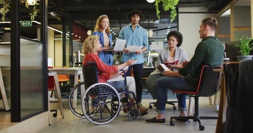 Happy disabled and diverse business people discussing work at office