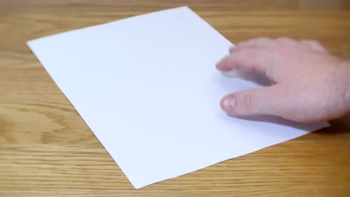 A sheet of blank white paper is placed on a wooden desk. A fountain pen is placed on top of the pape