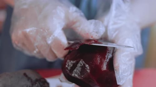 Weibliche Hände schneiden die Rote Beete mit einem Messer auf einem Küchenbrett
