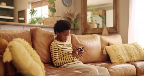 Boy Using Phone Sitting on Couch Indoors