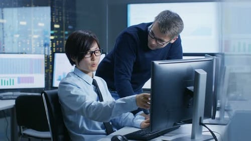 In the Data Mining Center Chief Statistician Consults His Young Assistant sits at His Workstation S