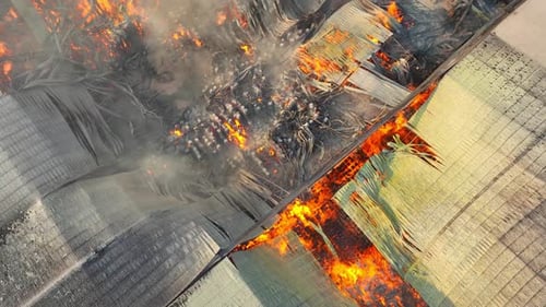 Une vue aérienne intense d'un incendie brûlant un bâtiment industriel.