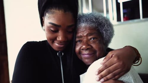 Young Woman Hugs Senior Woman Smiling Happily Indoors