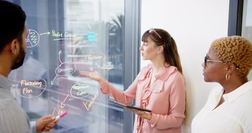 Colaborando no escritório, equipe discutindo estratégia de marketing em placa de vidro