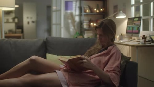Young Woman Reading Book Lying on Couch
