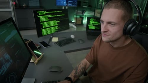 Joven programador masculino que disfruta escuchando música mientras trabaja en la oficina nocturna
