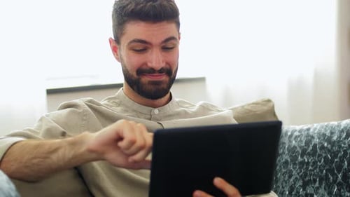 Bearded Man Using Tablet on Sofa