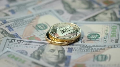 Une main humaine dépose des pièces d'or, de bitcoin, de dash et d'ethereum sur des billets en dollars