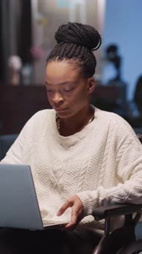 Eine Frau in einem Pullover benutzt ihren Laptop, um die technische Barrierefreiheit hervorzuheben