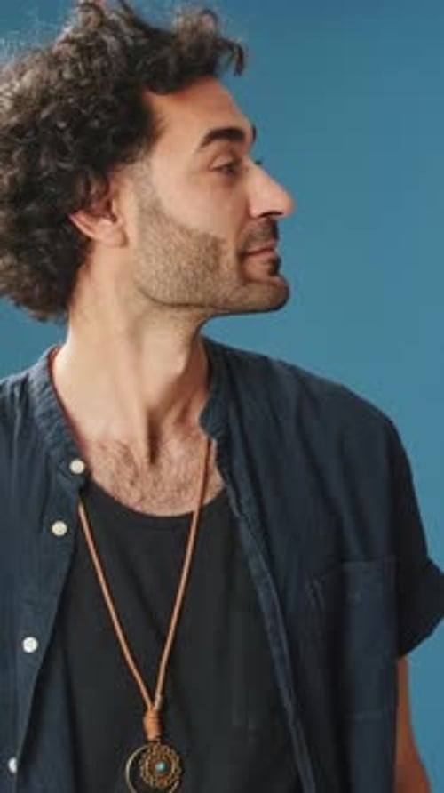 Surprised man looks to side to show copy-space isolated on blue background in studio