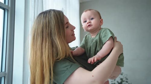 Loving Mother Holding Baby in Window Light