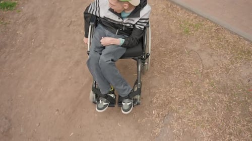 Teen in Wheelchair Outdoors Being Pushed by Other