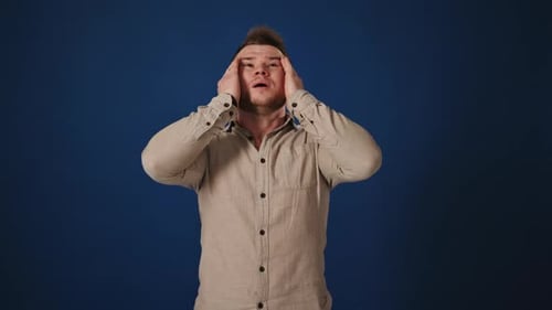 Man Reacting in Shock and Disbelief Against Blue