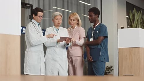 Medical Team Discussing Diagnosis on Tablet in Hospital
