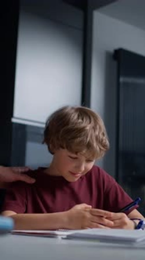 Young Boy Focusing Intently on Writing and Studying at a Desk Indoors with Natural Light Engaged in