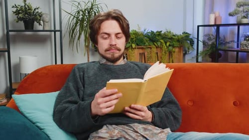 Man Relaxing Reading Book on Couch at Home