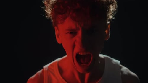 Portrait of Insane Man Yelling at Camera in Red Neon Lit Studio