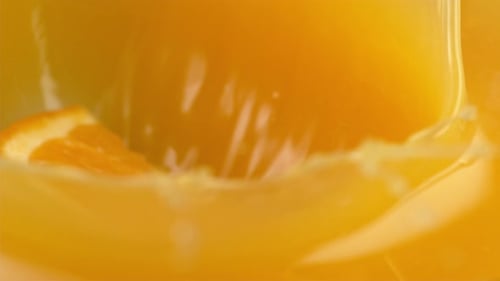 Orange Slice Drops Into Glass of Orange Juice