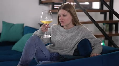 Woman Relaxes on Couch with Wine
