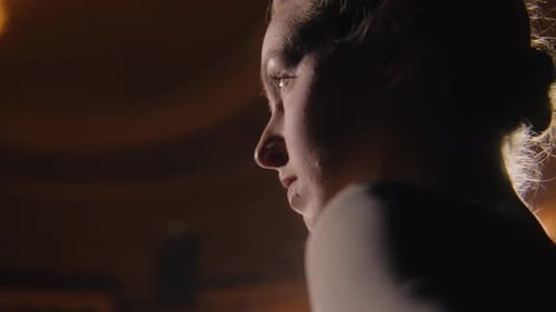 Concentrated Ballerina Stands on Theater Stage