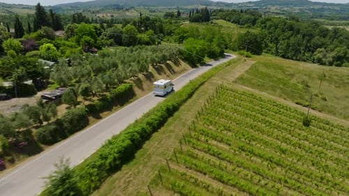 Drone following a Motorhom driving between vineyards and homs in Tuscany, Italy