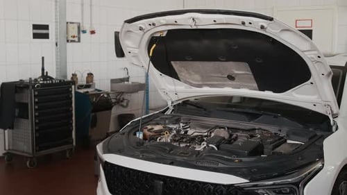 Coche sedán blanco genérico con capó elevado en el taller durante un chequeo regular