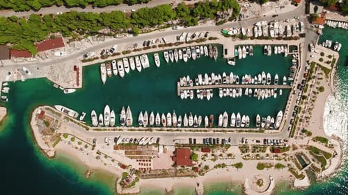 Boats and yachts moored on piers sit peacefully on water. Aerial view of structured nautical vessels