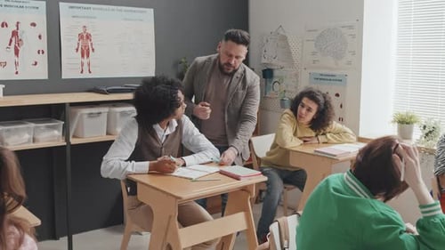 Teacher Helping Student in School Classroom
