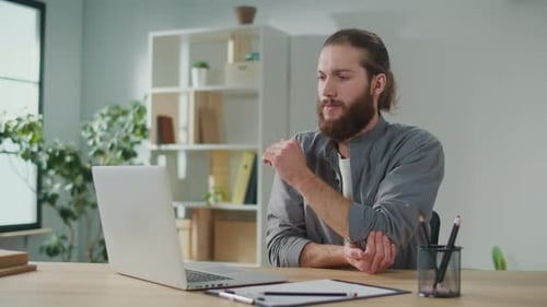 Man Working at Laptop Massages Sore Arm