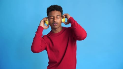 Young Adult Listens to Music with Headphones, Smiling