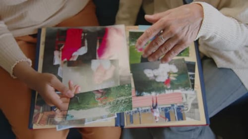 Manos de una joven y su abuela viendo el álbum de fotos