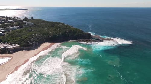 Aerial View of Waves Crashing Against Coastal Cliffs and Beach