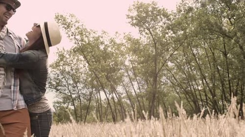 Young caucasian couple having fun together running in field on sunny autumn day