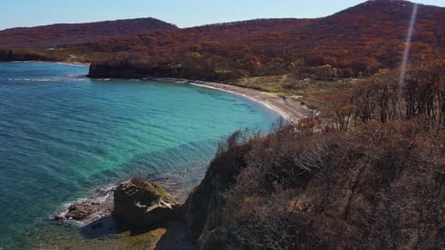 an Aerial View of a Cliff Overlooking a Body of Water with Mountains in the Background