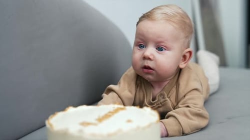 Adorable Baby Lying Next to Birthday Cake