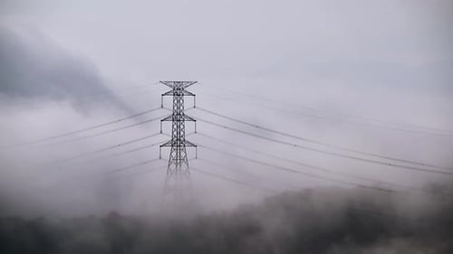 A high voltage tower and a sea of raging, tumbling clouds on a summer morning.