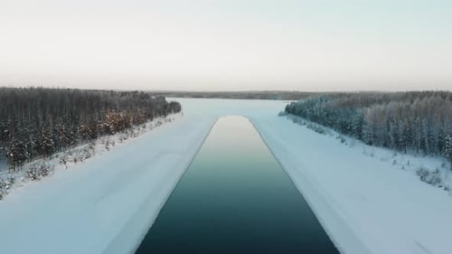 Aerial, reverse, drone shot, rising away from a iceless spot, on a river, on a sunny, winter day, in