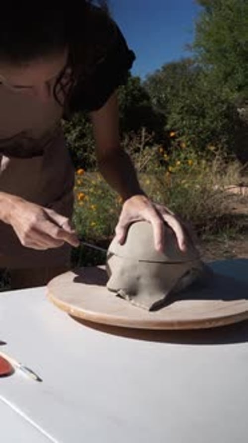Woman Sculpting Clay Outdoors on a Sunny Day