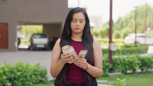 Young Woman Counting Money Outdoors in Daytime