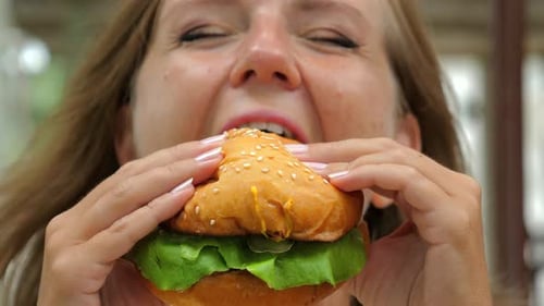 Woman Bites Into a Delicious Burger, Close-up