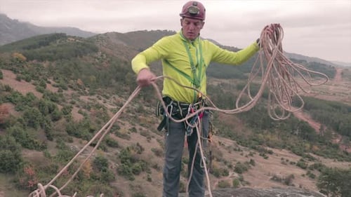 Climber collecting a rope preparing it for climbing. Male rock climber securing the climbing equipme