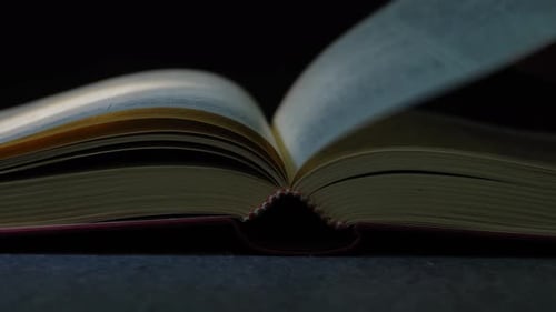 Hand Turning Pages in Open Book, Dark Setting