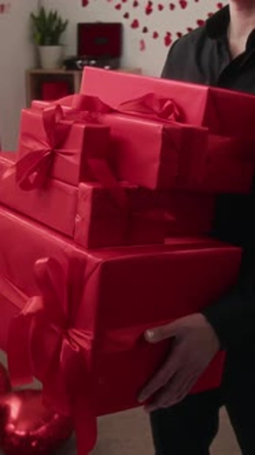 Vertical of Anonymous Man with Several Gift Boxes Wrapped in Red Paper