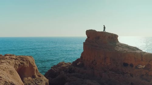 Adventurous travel girl walking at the edge of a cliff / rock and looking at a beautiful landscape.