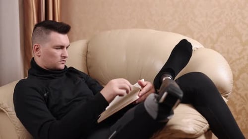 Young Adult Relaxing on Couch Reading Book