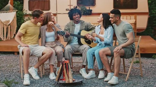 Friends Sing Around Campfire Near Camper