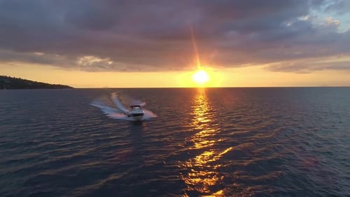 Aerial close up of a luxury speed boat coming in over the ocean at sunset.