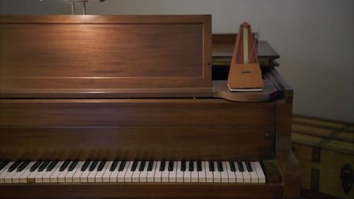 Upright Piano with Metronome in a Dimly Lit Room