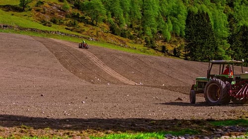Foto en movimiento rápido de tractores que aran un campo agrícola seco y polvoriento y preparan la tierra para sembrar en un c
